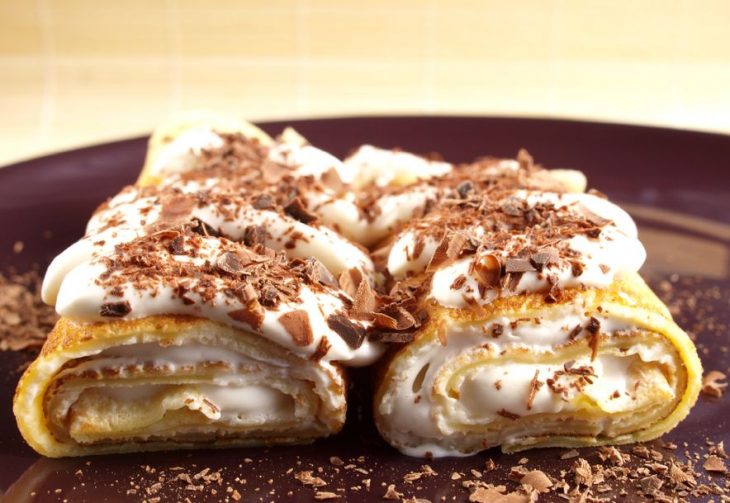 Crepas rellenas de queso crema cubiertas de crema chantilly y chocolate rallado