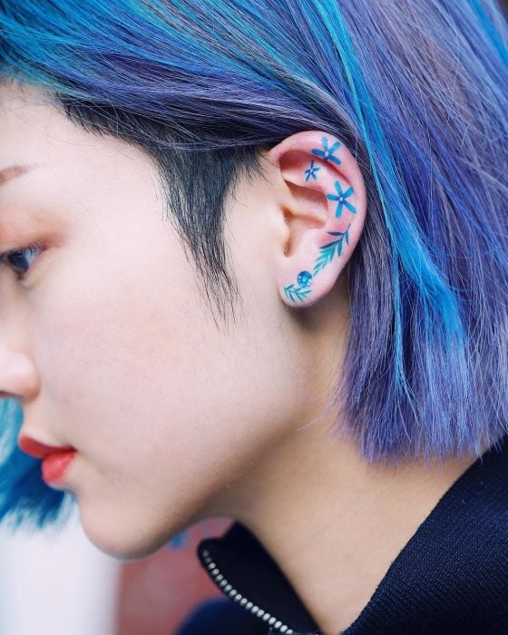 Tatuaje colorido de flores en la oreja hecho por la tatuadora coreana Zihnee