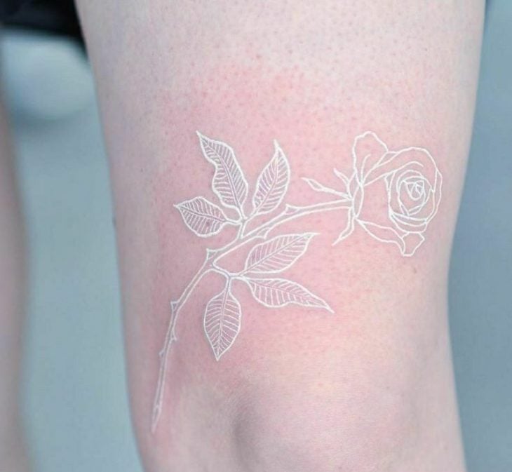 Tatuaje sobre el muslo en tinta blanca en forma de rosa