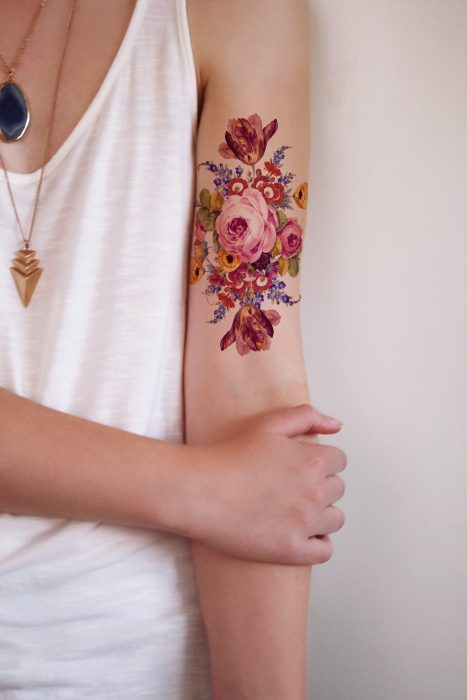 Mujer con tatuaje realista de flores en el brazo