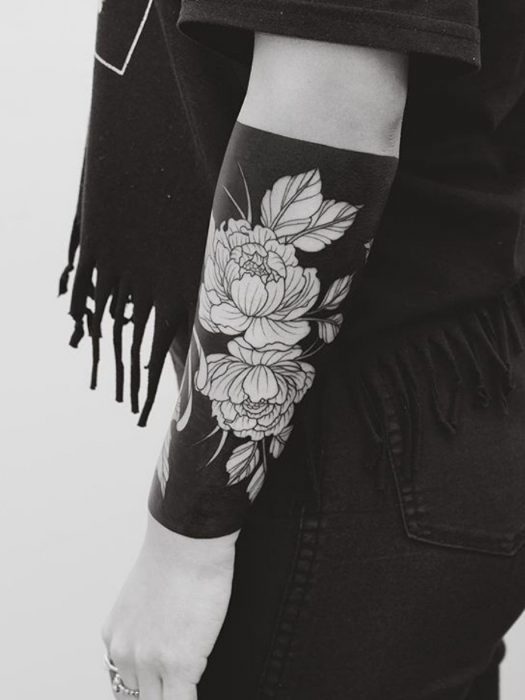 Mujer con tatuaje de flor en el brazo