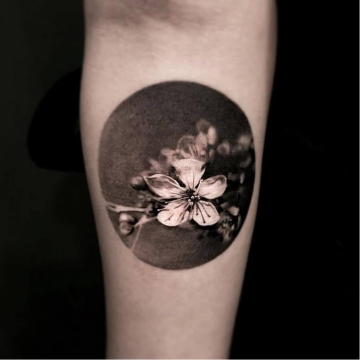 Mujer con tatuaje de flor realista en el brazo