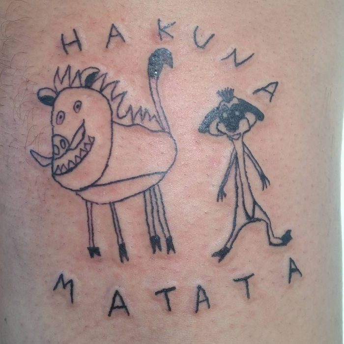 Tatuaje como dibujo infantil de Timón y Pumba del Rey León con la frase Hakuna Matata hecho por la tatuadora Helen Fernandes