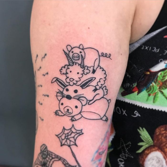 Tatuaje en el brazo con trazos sencillos de un oso, un conejo, un carnero y un cerdo uno encima del otro hecho por la tatuadora Helen Fernandes