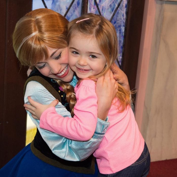 Chica vestida de Anna de la película de Frozen abrazando a una niña en Disneyland
