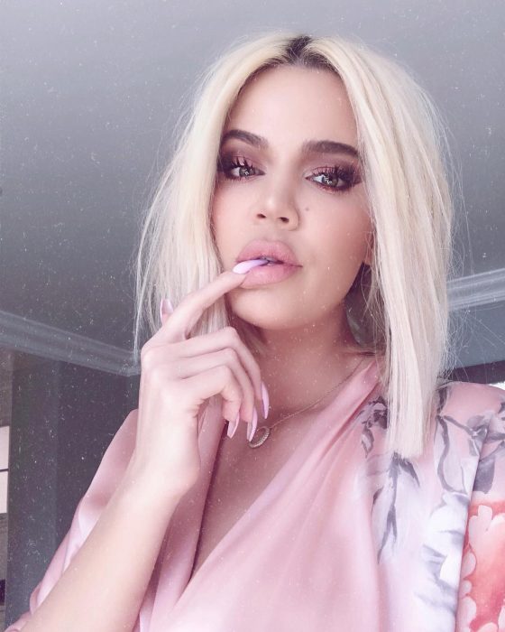 Khloé Kardashian posando para una foto de Instagram con el cabello corto planchado y una bata de color rosa 