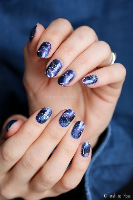 Manicura femenina de constelaciones, uñas con esmalte azul de universo con estrellas