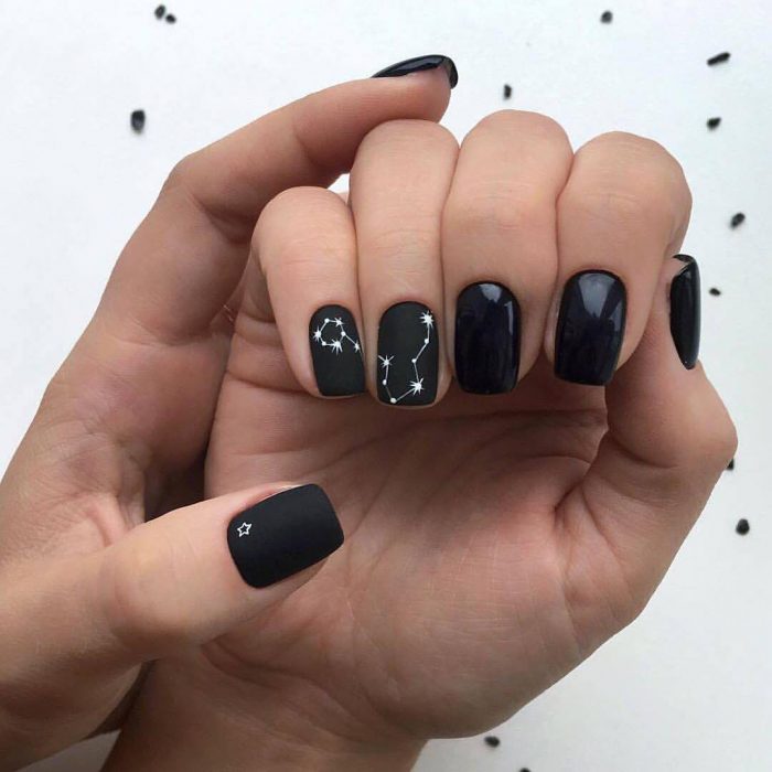 Manicura rockera y femenina de constelaciones con esmalte negro brillante y mate, y estrellas blancas