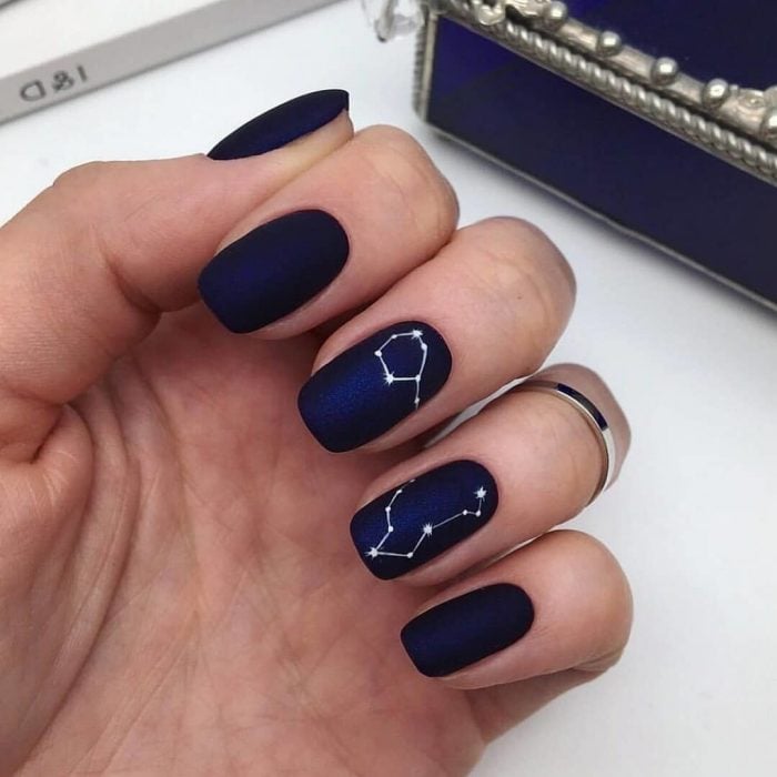 Manicura femenina y minimalista de constelaciones, uñas con esmalte color azul rey y estrellas