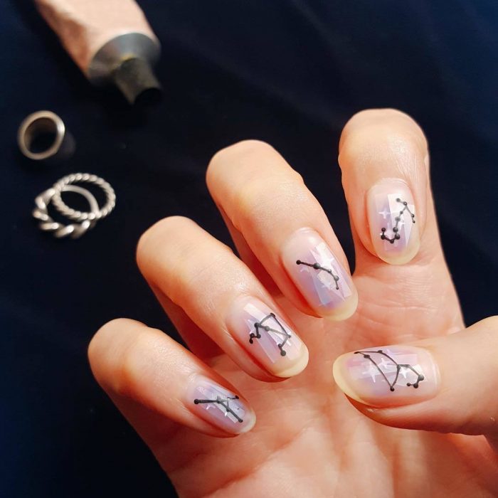 Manicura femenina y minimalista de constelaciones con esmalte transparente y negro