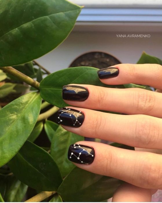 Manicura rockera y minimalista de constelaciones con esmalte negro y estrellas blancas