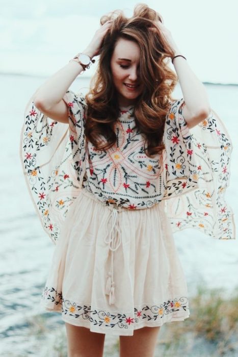 chica acariciando su cabello en vestido corto de encaje estilo boho