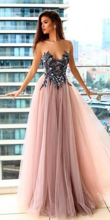 Chica en una terraza modelando un vestido con con detalles brillantes en el busto y falda de tul rosa 