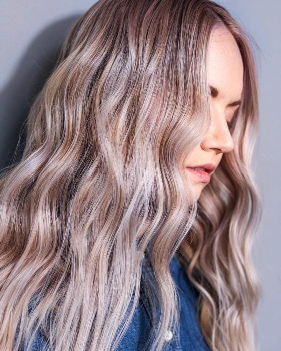 Mujer volteada d eperfil mirando hacia abajo cubriendo su rostro con su cabello color azúcar canela