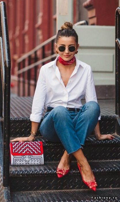 Chica modelando un atuendo de camisa de botones blanca, unos jens de mezclilla y un pañuelo rojo en el cuello