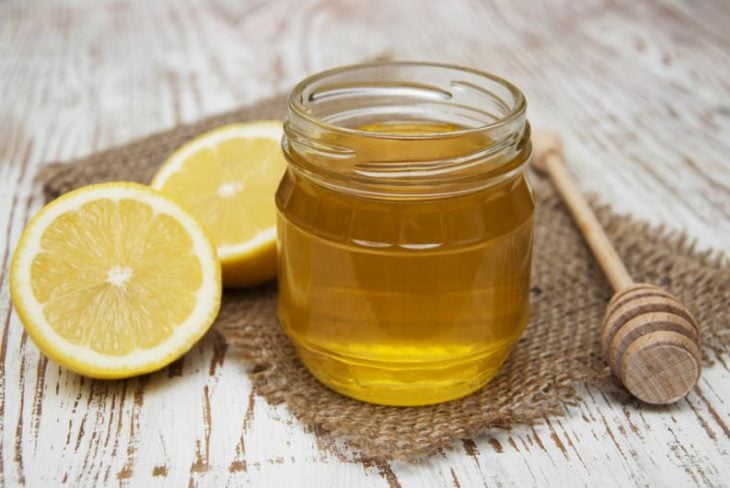 Tarro de miel y rodajas de limón sobre una mesa de madera 