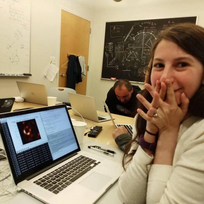 Joven científica, Katie Bouman, emocionada viendo en la computadora la primera fotografía tomada de un agujero negro gracias al algoritmo que desarrolló