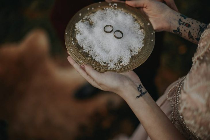 Pareja de novios celebra una boda nórdica al aire libre, anillos de compromiso en plato de sal