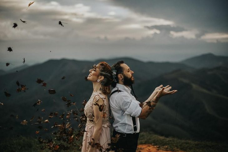 Boda vikinga, novios parados espalda contra espalda en una montaña con hojas secas