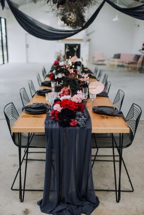 Mesas decoradas con flores rojas, platos oscuros, manteles negros para una boda estilo biker