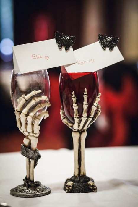 Par de copas para esposos con forma de calavera rellenas de vio rojo para una boda con estilo biker