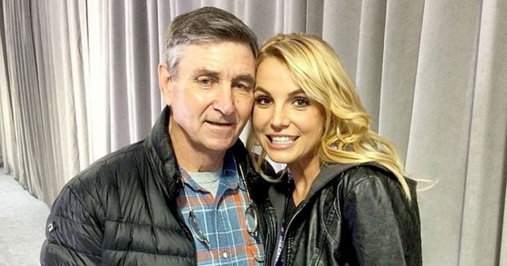 Chica recargada en el hombre de un hombre, ambos posando para una fotografía, hombre con chamarra negra de pluma de ganso, camisa a cuadros, cabello canoso, chica con chaqueta de mezclilla, sonriendo, cabello rubio, Britney y James Spears