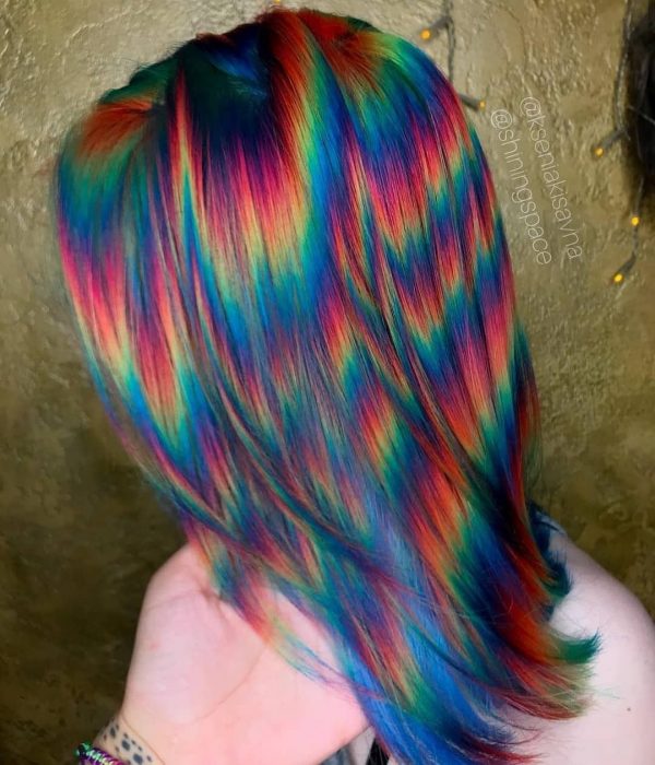 Mujer con cabello corto pintado con colores de fantasía que parecen destellos de luz, rosa, anaranjado, amarillo, verde y azul