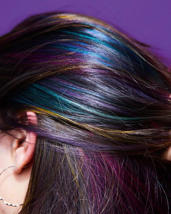 Tendencia de cabello, tinte oil slick que parece aceite derramado en el suelo, chica con reflejos de color azul, verde, amarillo, rosa y morado