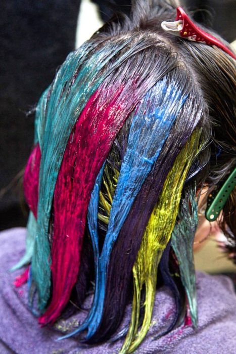 Tendencia de cabello, tinte oil slick que parece aceite derramado en el suelo, chica aplicándose tinte de colores rosa, azul, amarillo y verde