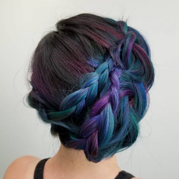 Tendencia de cabello, tinte oil slick que parece aceite derramado en el suelo, chica con peinado de trenza recogido, cabellera de colores morado, castaño y azul