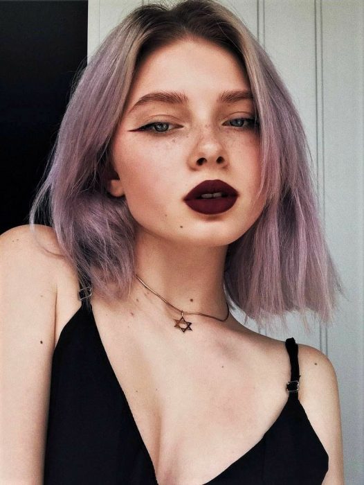 Chica indie con pecas, delineado cat eye, labal rojo vino y cabello corto y lacio color gris lavanda o lavender gray con tonalidad rosa