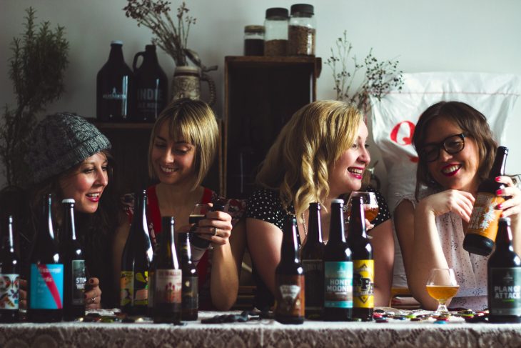 Grupo de cuatro amigas sentadas en una mesa bebiendo cerveza artesanal