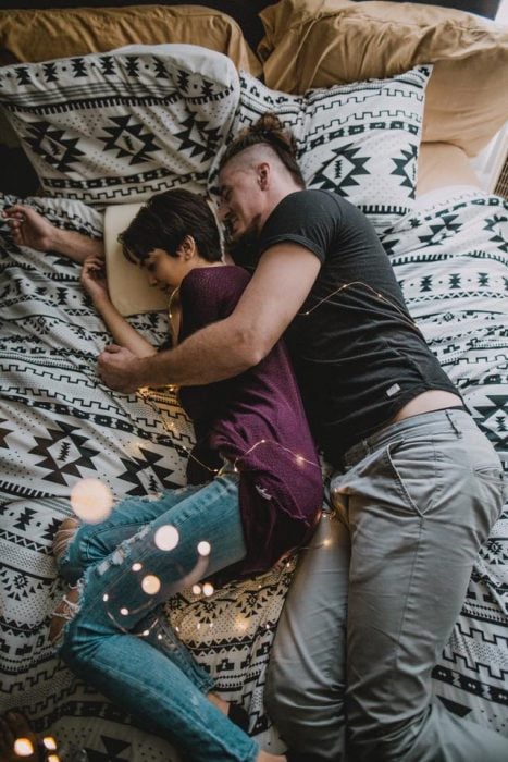 Pareja de novios dormidos sobre una cama, abrazados como cucharitas usando la almohada Coodle Pillow