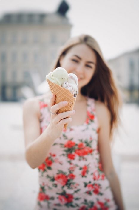 Chica sosteniendo un barquillo de galleta con helado de vainilla entre sus manos