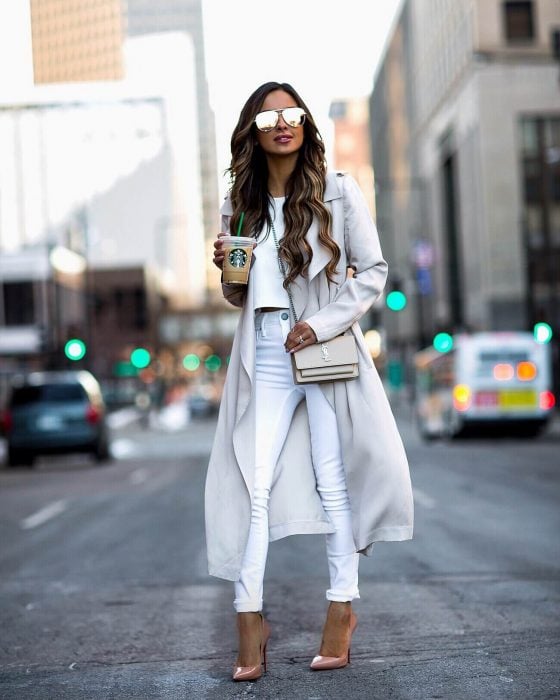 Chica caminando por la calle con atuendo en color blanco, con jeans y saco