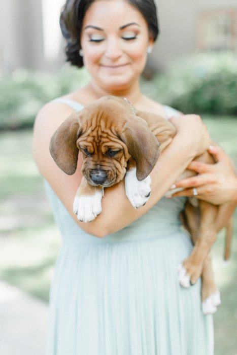 Dama de honor con vestido color menta sosteniendo a un cachorro en lugar de un ramo de flores 