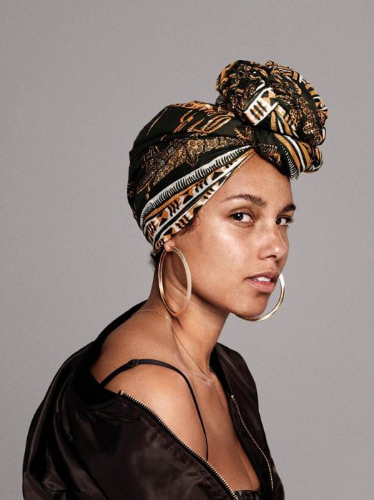  Alicia Keys mirando de perfil, con suetér negro, blusa de tirantes, mascada en la cabeza, arracadas grandes