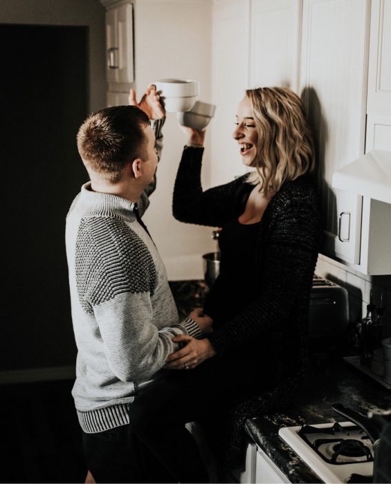 Par de novios chocando sus tazas de café, sonriendo, charlando en la cocina 