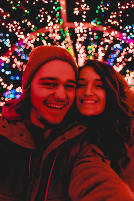 Pareja de novios tomando una selfie de ellos en una feria de pueblo con luces de colores