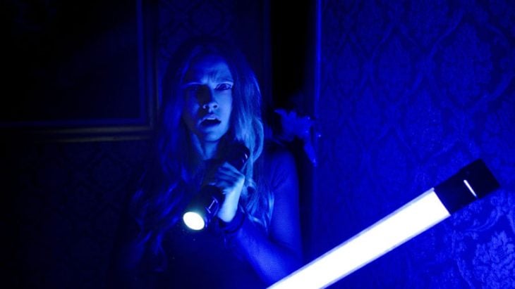 Mujer temerosa sosteniendo una lampara de luz led entre sus manos escena de la película Cuando las luces se apagan