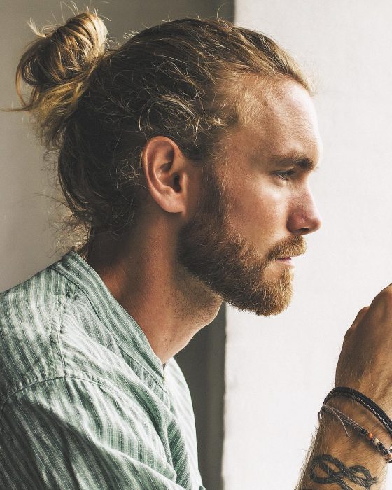 Niels Horvath, hombre de perfil, de cabello rubio con man bun, con barba y bigote corto,