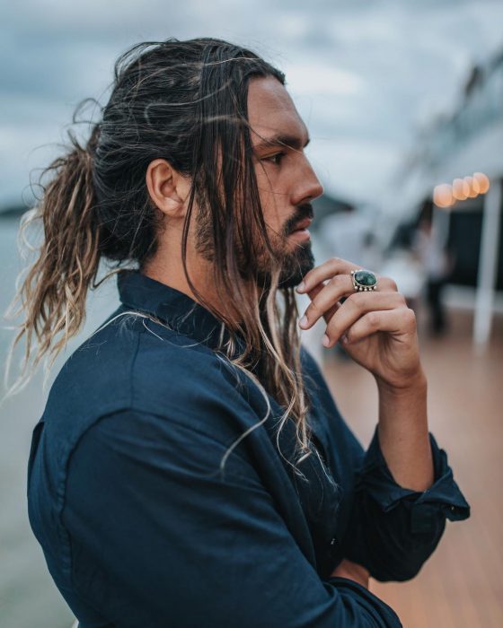 Pedro Giannini, perfil de hombre bronceado con cabello largo teñido, con barba y bigote corto