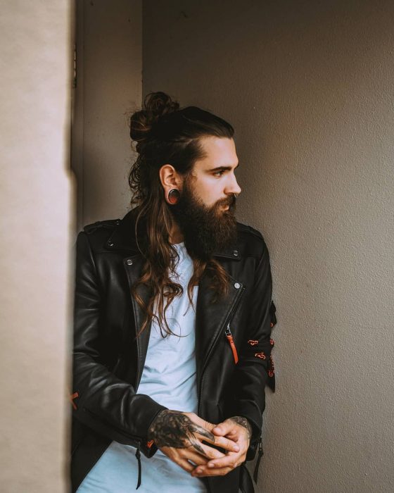 Philip Bottenberg, hombre rockero con cabello castaño largo, recogido con man bun, barba y bigote tupido, con tatuajes en las manos y expansiones en las orejas