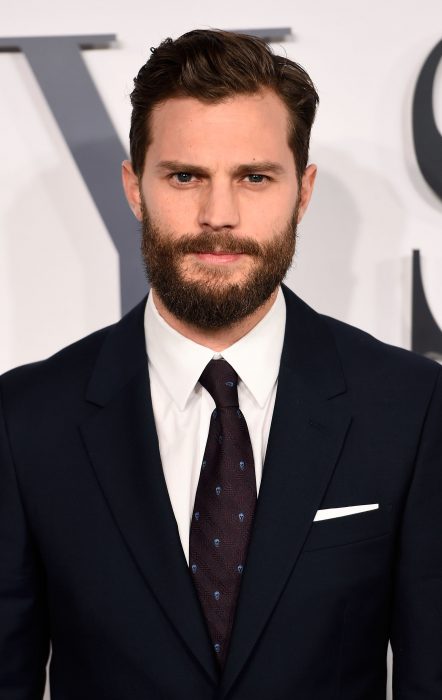 Actor Jamie Dornan, hombre de cabello corto y castaño, barba y bigotes largos, smoking de gala azul oscuro