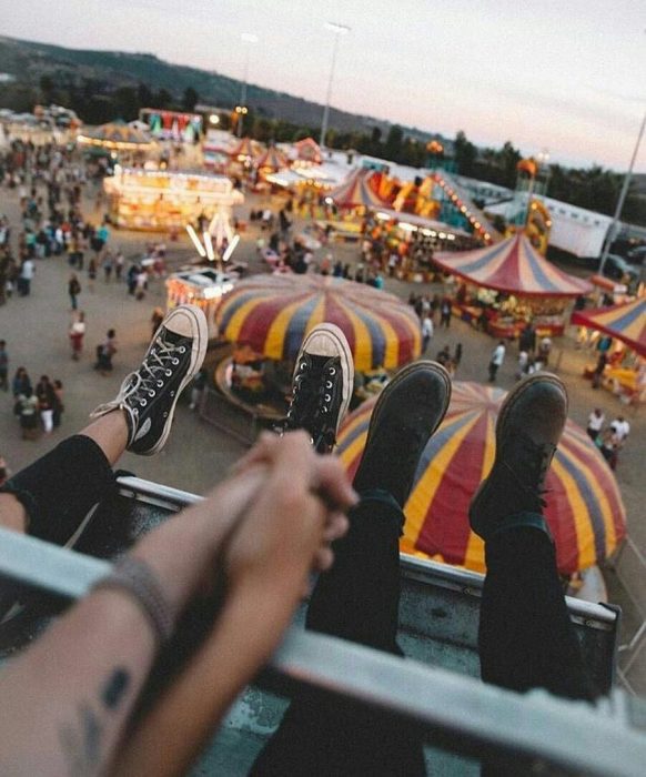 Pareja tomada de las mano en un juego mecánico dentro de un parque de diversiones