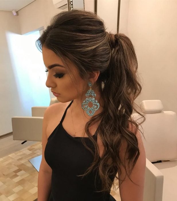 Girl modeling her curly hairstyle in a ponytail