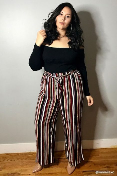 Chica modelando una blusa negra y un pantalón en rayas