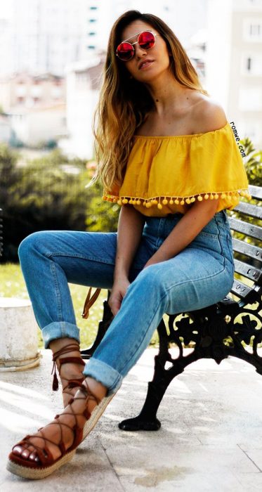 Chica modelando unos jeans de mezclilla y una blusa de hombros descubiertos en color amarillo