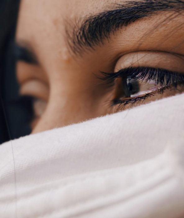 Rostro de una mujer cubierto con una seda blanca que solo deja ver sus ojos llorosos 