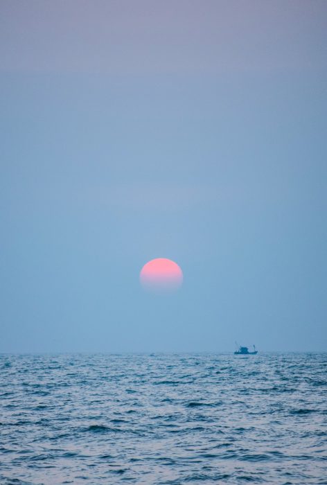 Luna Rosa a medio tardecer sobre la costa del mar 